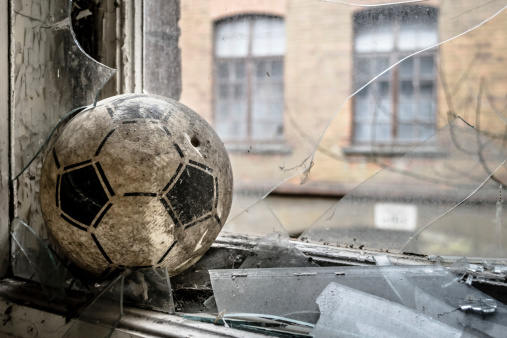 An old little football shot into a glass pane