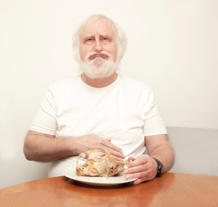 senior bearded male with indigestion after eating roast chicken , has eaten and drunk too much