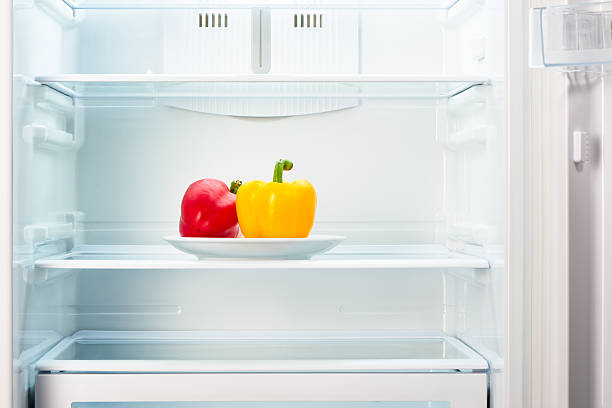 istock Red and yellow peppers on white plate in open refrigerator 484348544