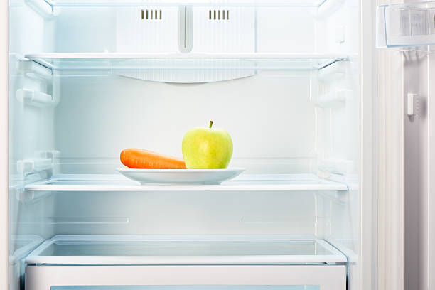 istock Green apple and orange carrot on white plate in refrigerator 484348546