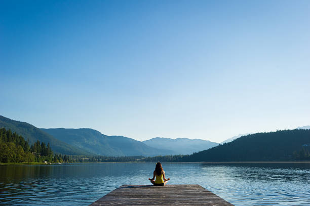 Easy Pose Tranquil Lakeside meditation at sunrise Female meditating doing sukhasana or Easy Pose during a yoga working at a pristine mountain lake meditating stock pictures, royalty-free photos & images