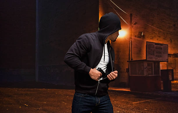 Gangster carrying gun Gangster carrying gunhttp://www.twodozendesign.info/i/1.png man holding gun at night in the city stock pictures, royalty-free photos & images