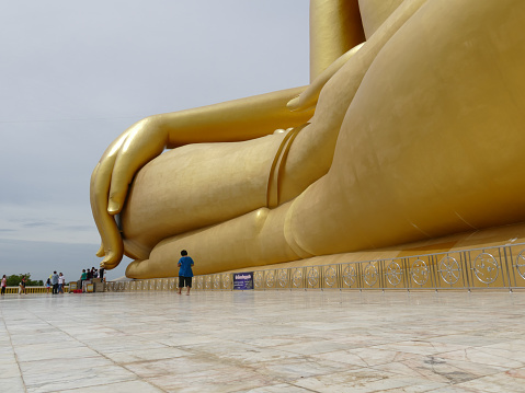 Ang Thong, Thailand - August 1, 2015: buddhist people touch the finger of big golden buddha statue in Muang temple.