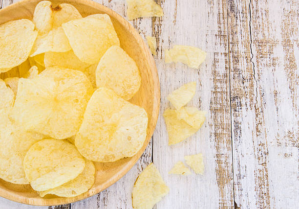 istock Potato chips in wooden plate on white wooden table 484374532