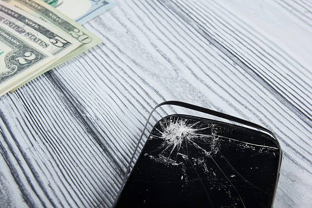 istock Modern broken mobile phone and money on white wooden background. 484374722