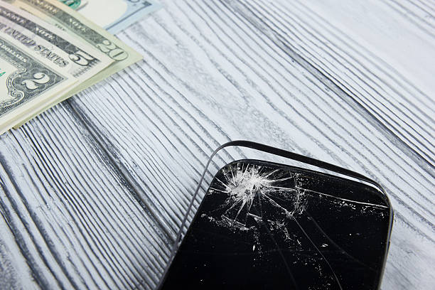 Modern broken mobile phone and money on white wooden background. Modern broken mobile phone and money on white wooden background. Copy space. Top view broken digital tablet note pad cracked stock pictures, royalty-free photos & images