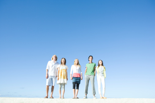 Young people standing under blue sky