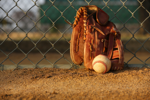 Baseball and Glove against the Field Fence