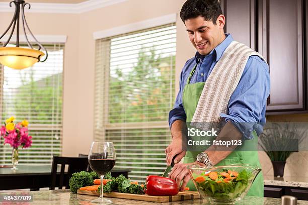 Latin Man Prepara La Cena En Casa Cocina Hace Saludables Ensaladas Foto de stock y más banco de imágenes de Cocinar