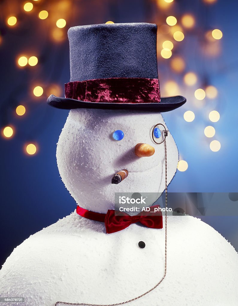 Snowman Gentleman Snowman dressed as gentleman with hat, bow tie, monocle, and cigar. He is placed in front of blurred christmas lights background Blue Stock Photo