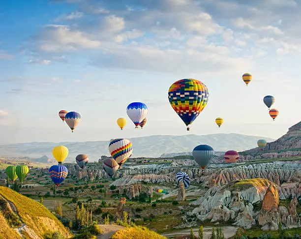 Colorful hot air balloons flying over Red valley at Cappadocia, Anatolia, Turkey. Volcanic mountains in Goreme national park.