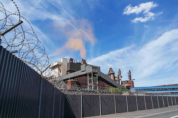 istock Steelplant with barbwire fence producing red cloud 484385066