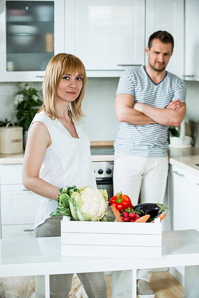 istock Woman with vegetable box in kitchen, man looking sceptical 484389376
