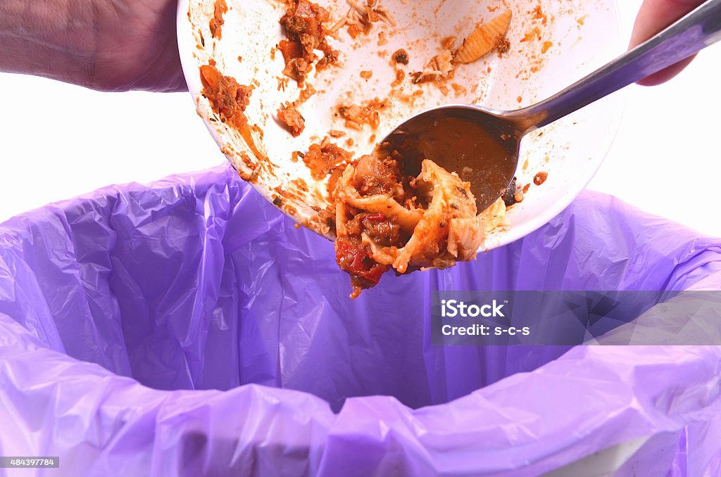 Scraping leftover food from a bowl into a garbage bag A person removes leftover food into a bin Scraping Stock Photo