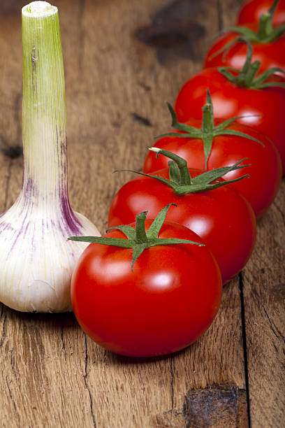 istock Fresh ripe Tomatoes and garlic bulb in a Row 484398555
