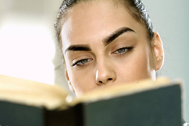 istock Young woman on sofa reading a book 484408146