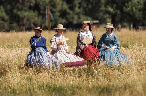 Graeagle,California, United States-July 4, 2015: Four women dressed in Civil War era clothing sit and await the start of a skirmish during a Civil War reenactment,
