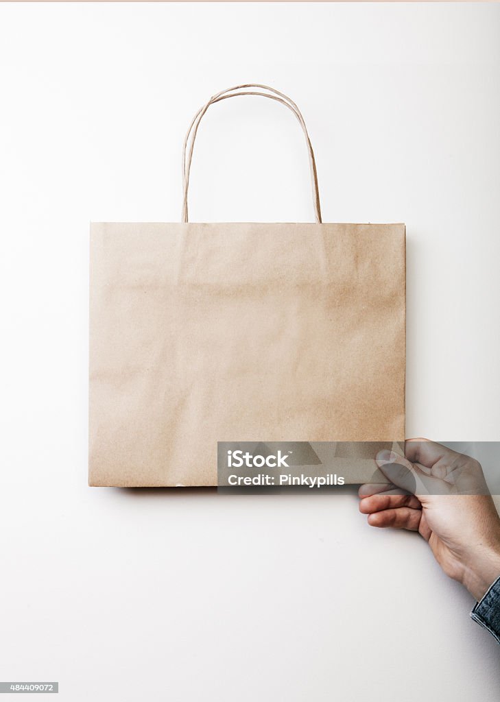 Mockup of craft shopping bag Mock up of craft square bag holding in a hand on the white background 2015 Stock Photo