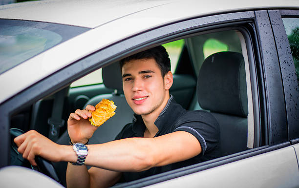 istock Young man driving his car while eating food 484409222
