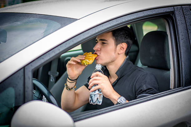 istock Young man driving his car while eating food 484409252