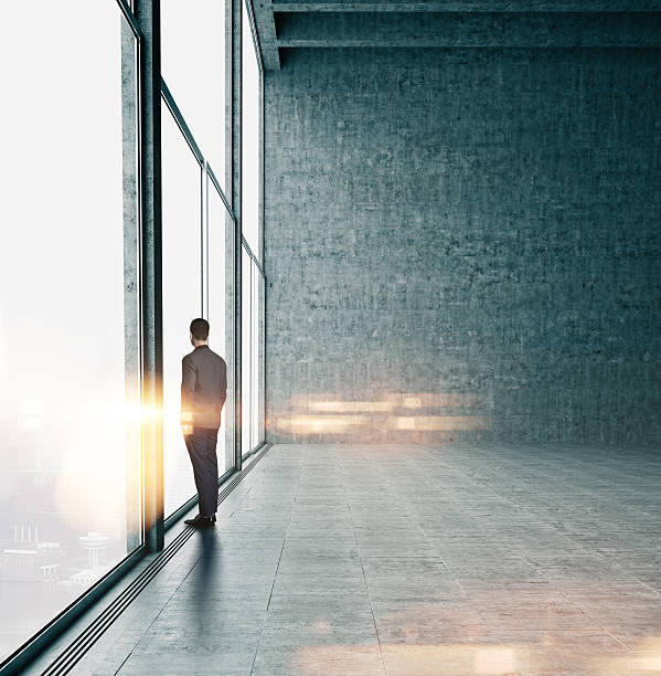 istock Businessman looking at sunrise in office 484411482