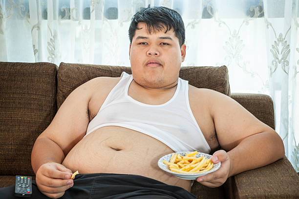 gordo preguiçoso homem sentado com comida rápida - remote fat overweight dieting imagens e fotografias de stock