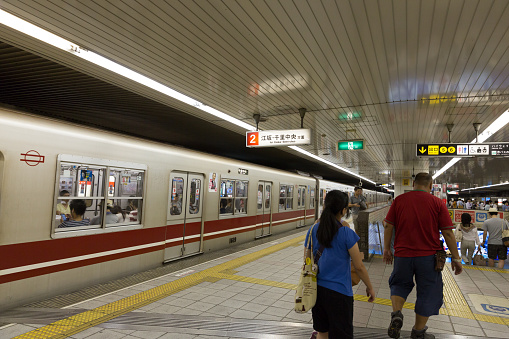 Osaka, Japan - July 26, 2014: People at Shin-Osaka Station in Osaka Prefecture, Japan. This train is on Midosuji Line going to Senri-Chuo Station. It is operated by the Osaka Municipal Subway. 