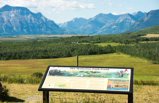 Waterton, Canada - July 29, 2015: Rocky Mountains view point sign in Southern Alberta, Canada.The Rocky Mountains are in the background. The mountains of Glacier and Waterton National Parks are in the background. The sign indicates the scene from the view point.