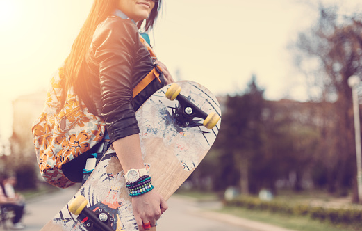 Smiling girl holding skateboard outside