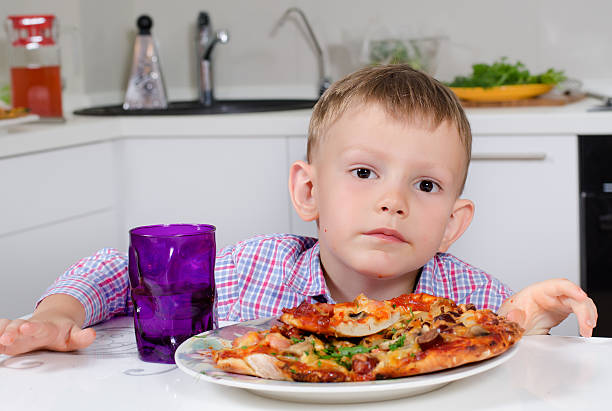 istock Little boy eating a big plate of pizza 484423006