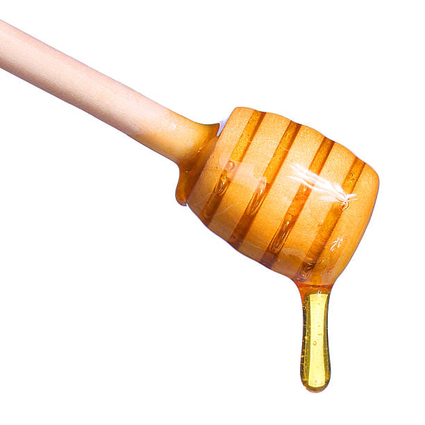 istock Honey dripping from wooden honey dipper isolated 484427822