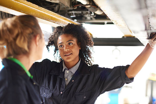 istock female garage mechanics under a car 484427860