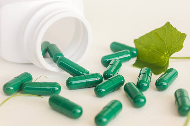 istock Herb in green capsule spilling out of a bottle 484428034