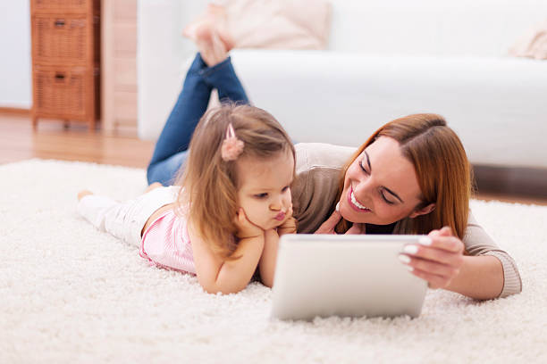 istock Focus little girl with mom using digital tablet at home 484429979