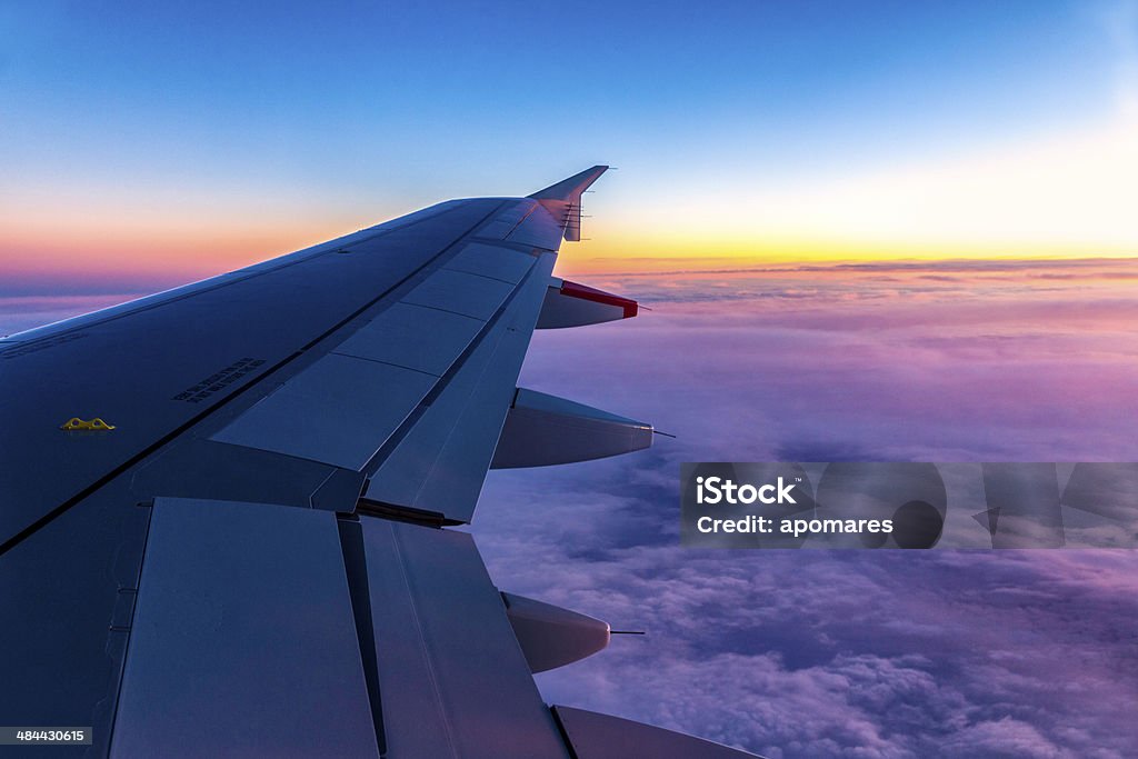Classic image of wing clouds and wingtip on comercial airplane Multicolored sunrise with fluffy clouds on comercial airplane. Commercial Airplane Stock Photo