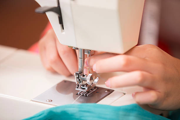istock Seamstress sews fabric, clothing with sewing machine. Close-up. 484432508