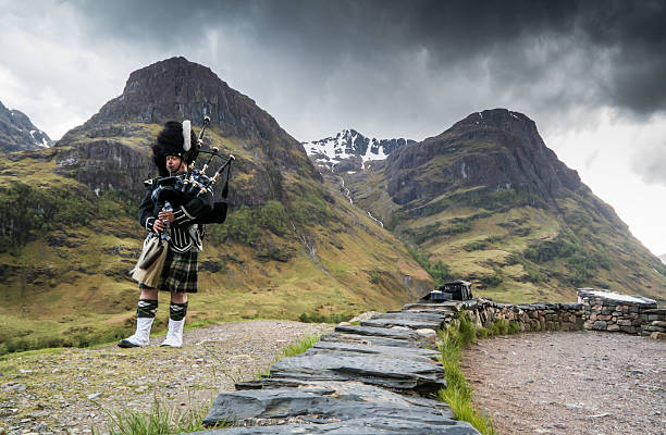 joueur de cornemuse traditionnel dans les highlands d'écosse de glencoe - bagpipe photos et images de collection