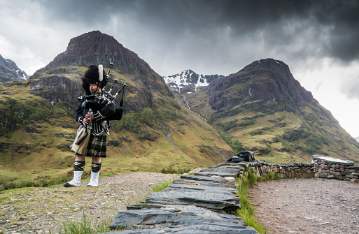Traditional bagpiper in the scottish highlands by Glencoe