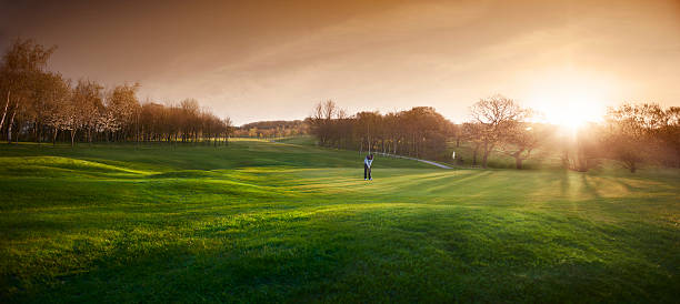 leuchtendes golfplatz mit golfspieler auf dem putting green - golf golf flag sunset flag stock-fotos und bilder