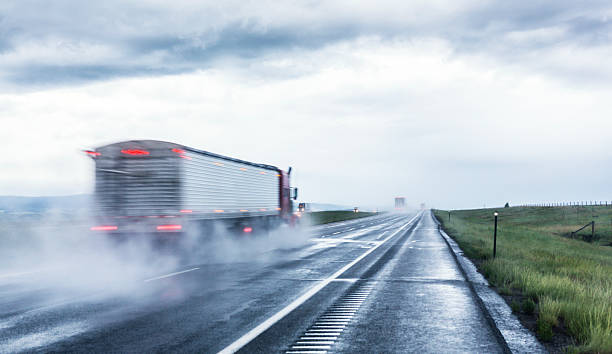 Speeding Expressway Tractor Trailer Trucks A blurred semi tractor trailer truck streaks away on a rain-soaked expressway highway on a stormy day. truck rain stock pictures, royalty-free photos & images