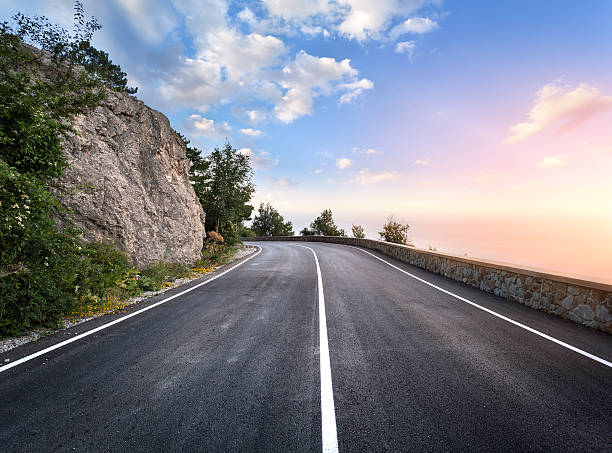 strada asfaltata in estate foresta al tramonto. monti di crimea - dividing line single line striped in a row foto e immagini stock