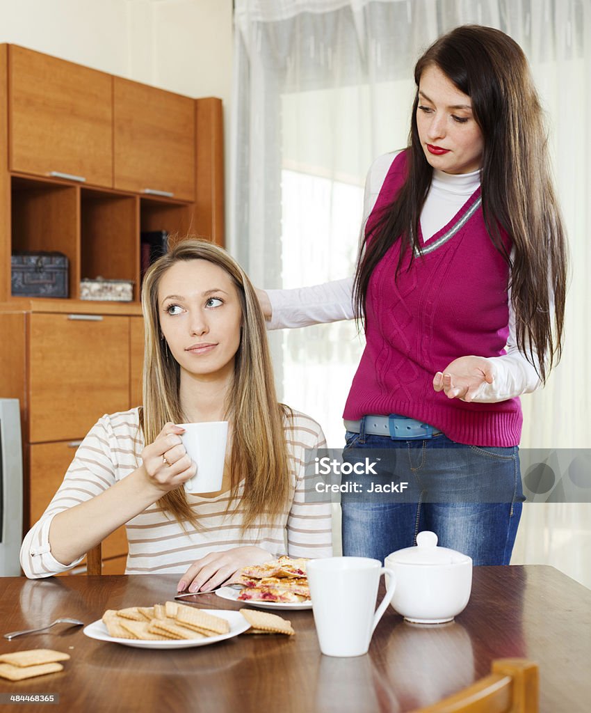 Two women having quarrel Two women having quarrel  at table in home Adult Stock Photo