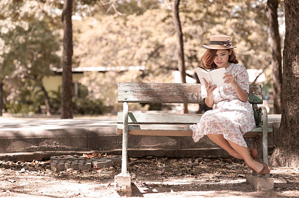 istock Vintage girl reading book in park 484468725