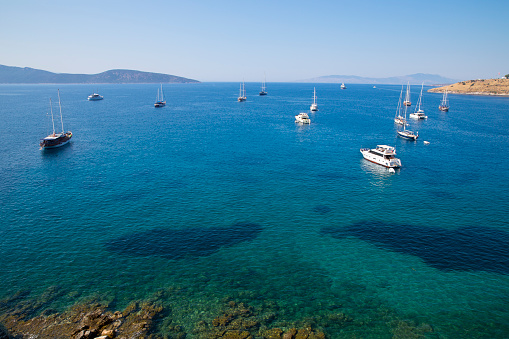 Boats, sailboats and yachts are on the way out to deep blue sea near Mediterranean sea coast. View on sea and lots of ships