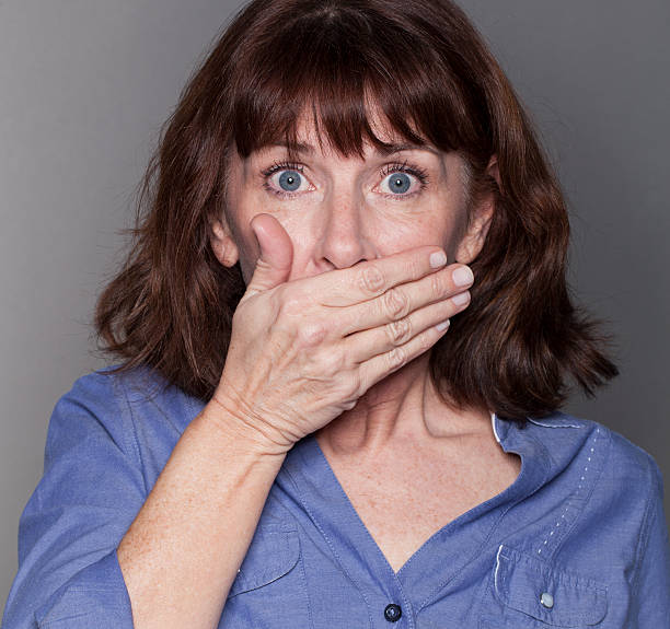 istock surprised attractive mature woman hiding her mouth 484471596