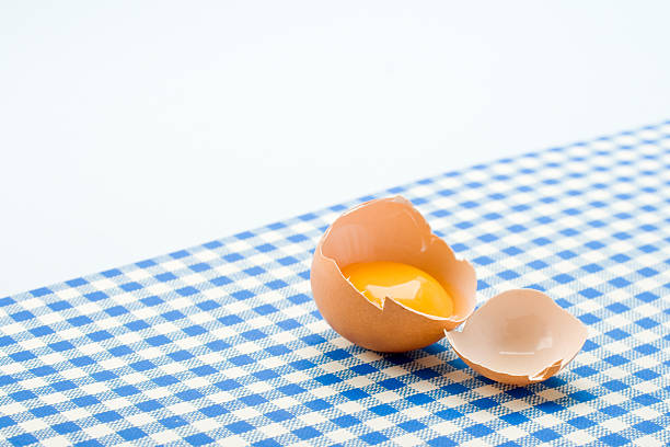 broken egg on blue napkin stock photo