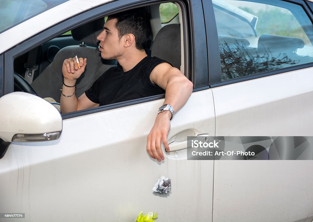 Man Tossing Litter from Open Car Window Detail of Man Wearing Wrist Watch Tossing Crumpled Ball of Refuse Out of Car Window onto Ground, Close Up of Irresponsible Man Littering Garbage from Car Car Stock Photo