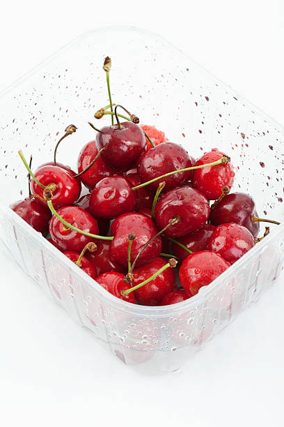 istock Close up of cherries in plastic container on white background 484477306
