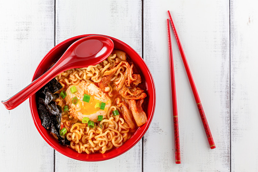 A bowl of spicy Korean ramen with egg, kimchi, seaweed and green onion.