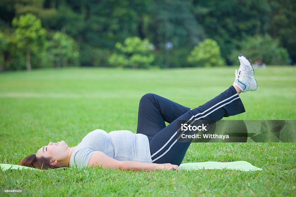 a woman lying by exercise leg upwards Asian a woman lying by exercise leg upwards at the park Asia Stock Photo